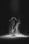 Dancer in a dark setting with dust or sand around