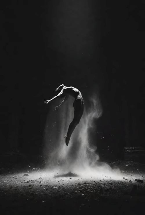 Dancer in a dark setting with dust or sand around