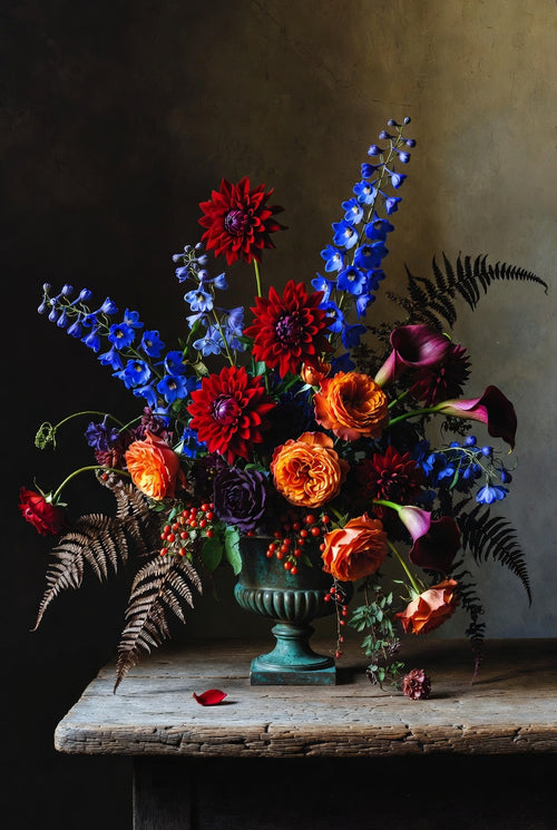 Colorful flower arrangement in a green vase on a wooden table with a dark background