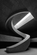Concrete spiral staircase with a light source at the top, creating a dramatic effect.